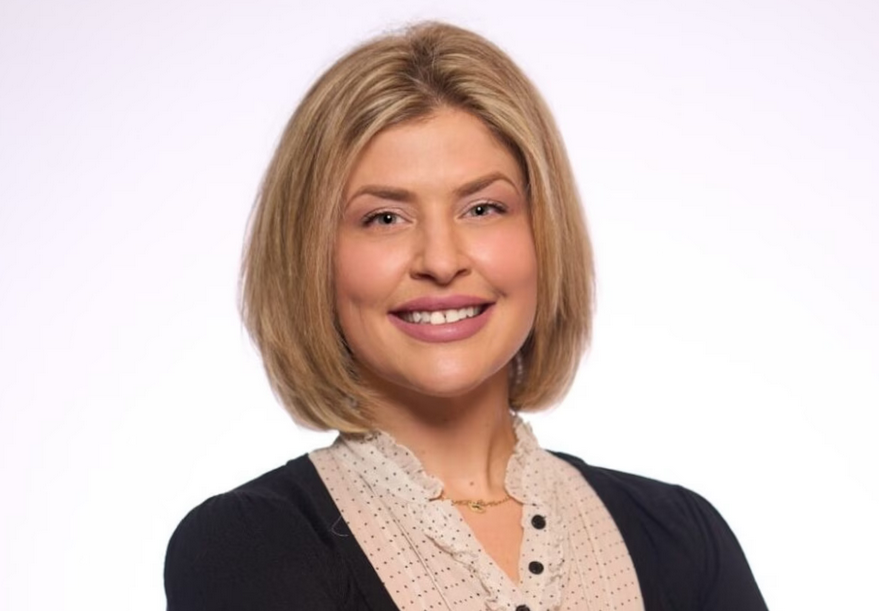 White woman with a blonde bob haircut smiles